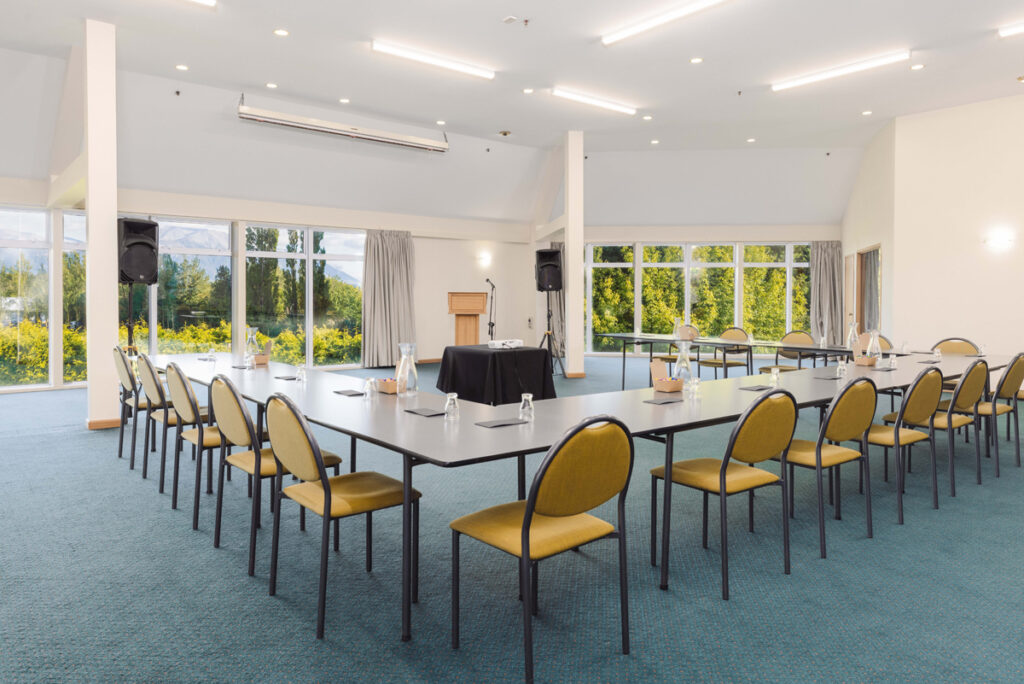 Spacious conference room at Methven Resort with U-shaped setup, natural light, and views of the mountains and gardens.