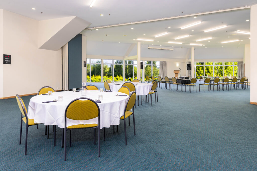Spacious function room at Methven Resort set in banquet style with round tables, natural light, and scenic garden views.