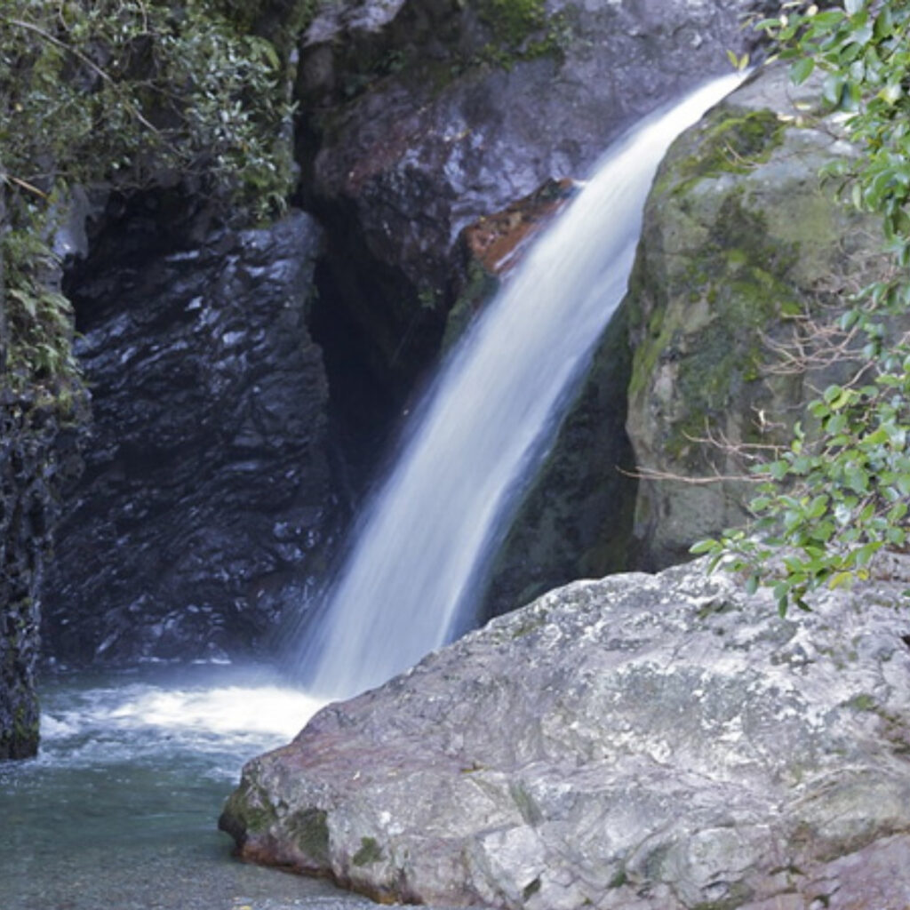 Scenic waterfall flowing over mossy rocks into a clear pool near Methven, Canterbury.